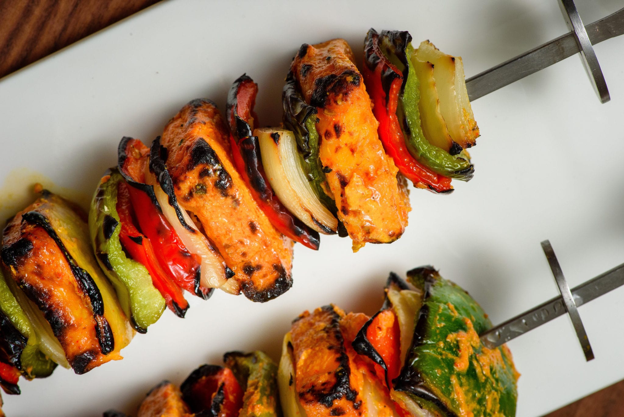 Skewers of chicken tikka kabob with charred peppers and onions, fresh off the tandoor.